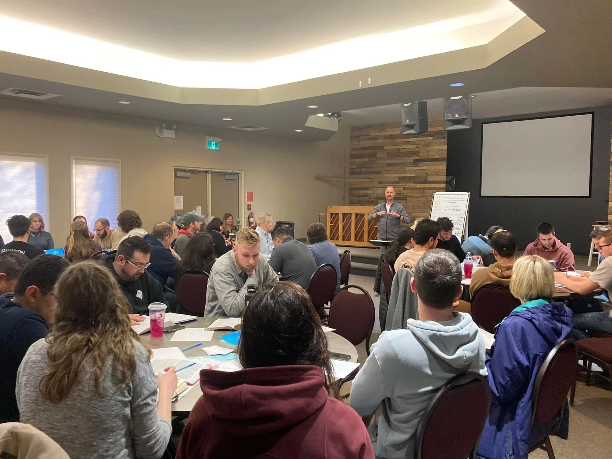 Líderes sentados alrededor de las mesas en una capacitación del 10:2 Network